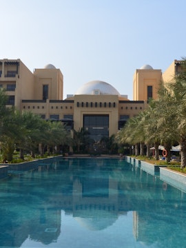 Luxury resort pool with palm trees in Ras Al Khaimah, UAE.