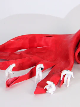 Miniature figures inspecting a large red glove at the Banksy exhibition in Madrid.