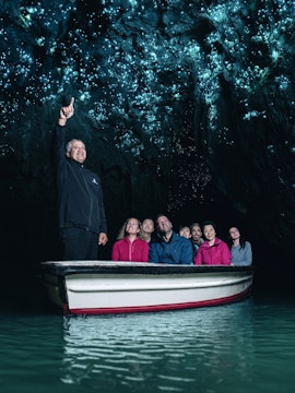 Tourists on a boat in Waitomo Caves, Auckland, viewing glowworms on the cave ceiling.