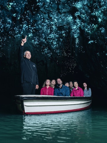 Tourists on a boat in Waitomo Caves, Auckland, viewing glowworms on the cave ceiling.