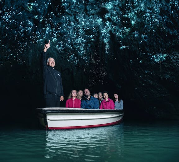 Tourists on a boat in Waitomo Caves, Auckland, viewing glowworms on the cave ceiling.