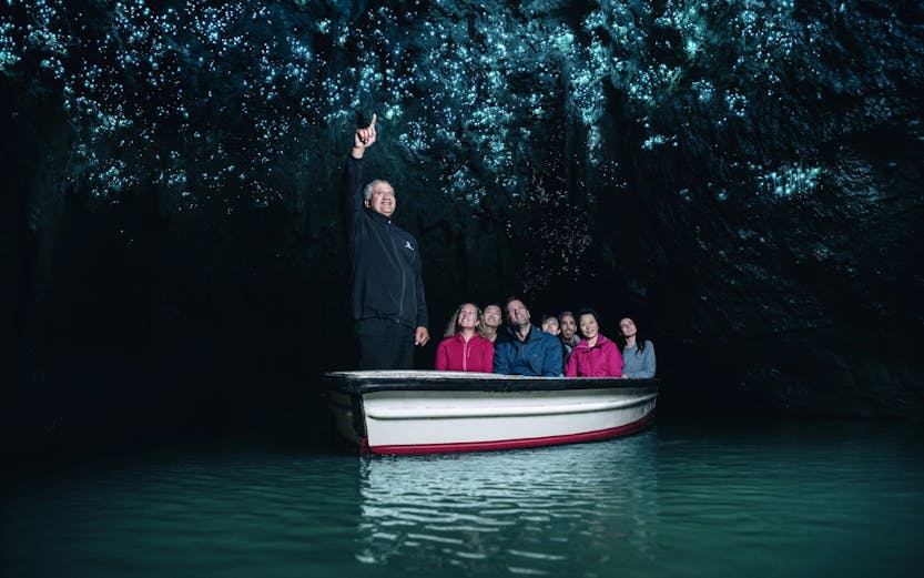 Tourists on a boat in Waitomo Caves, Auckland, viewing glowworms on the cave ceiling.
