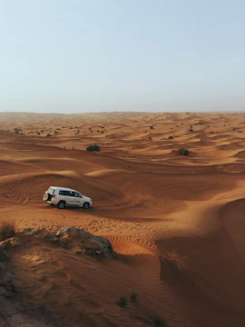 SUV driving through Dubai desert dunes.
