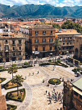 Palermo cityscape with Museo Salinas courtyard, historic buildings, and mountains in the background.