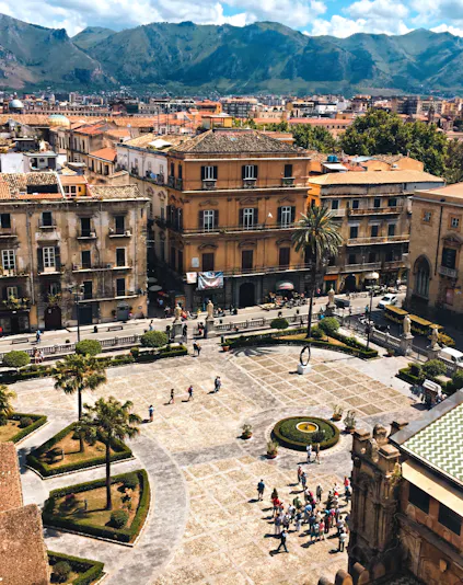 Palermo cityscape with Museo Salinas courtyard, historic buildings, and mountains in the background.