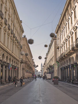 Street view of Via Roma in Turin, Italy, with arched buildings and hanging decorations.