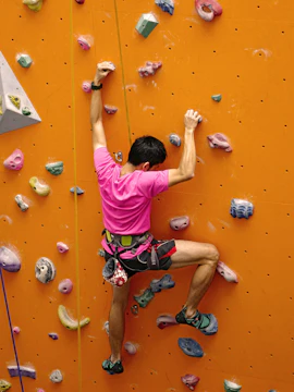 Person climbing an orange rock wall at Aventura Park, Dubai.