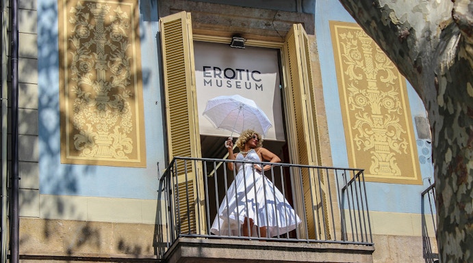 Woman in white dress with umbrella on balcony of Erotic Museum, Barcelona.