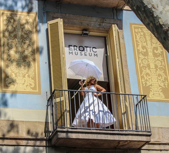 Woman in white dress with umbrella on balcony of Erotic Museum, Barcelona.