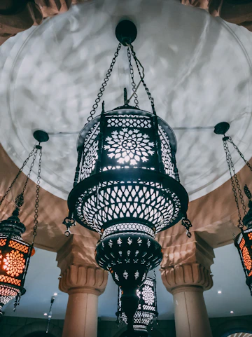 Ornate lanterns hanging from an arched ceiling in Sharjah.