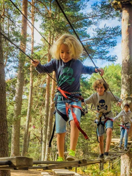 Children navigating a treetop adventure course at Aventura Amazonia, Madrid.