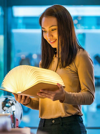 Visitor exploring illuminated book at Red Dot Design Museum, Singapore.