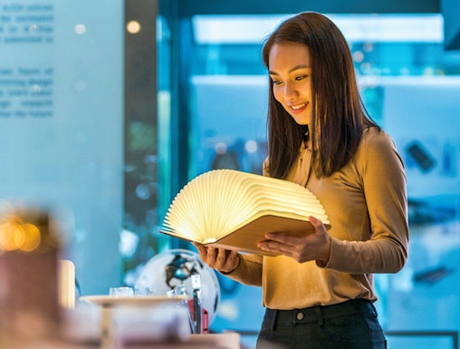 Visitor exploring illuminated book at Red Dot Design Museum, Singapore.