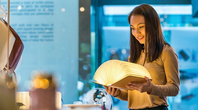 Visitor exploring illuminated book at Red Dot Design Museum, Singapore.