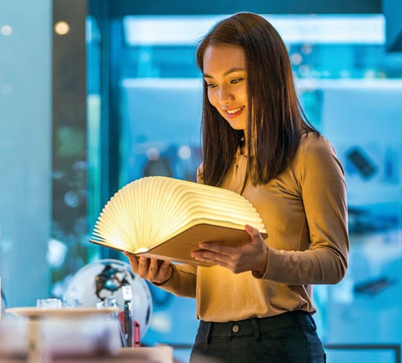 Visitor exploring illuminated book at Red Dot Design Museum, Singapore.