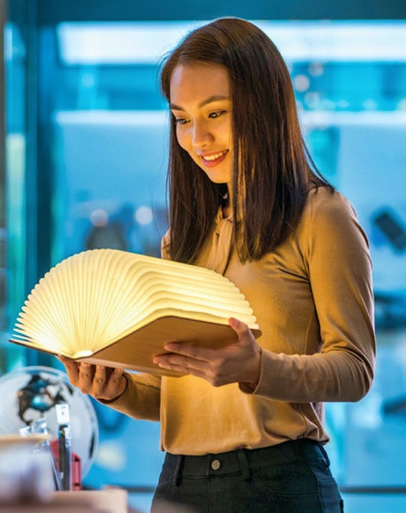 Visitor exploring illuminated book at Red Dot Design Museum, Singapore.