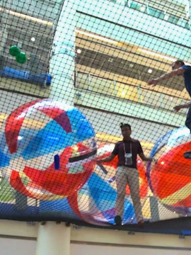 Visitors walking on suspended net with giant balls at Air Zone, Singapore.