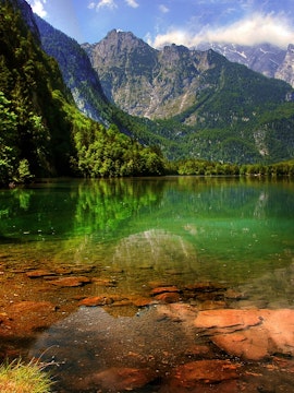 Berchtesgaden lake with mountain reflections and lush greenery.