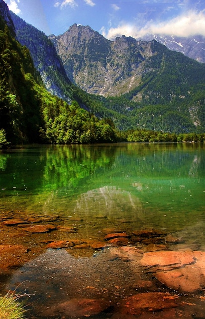 Berchtesgaden lake with mountain reflections and lush greenery.
