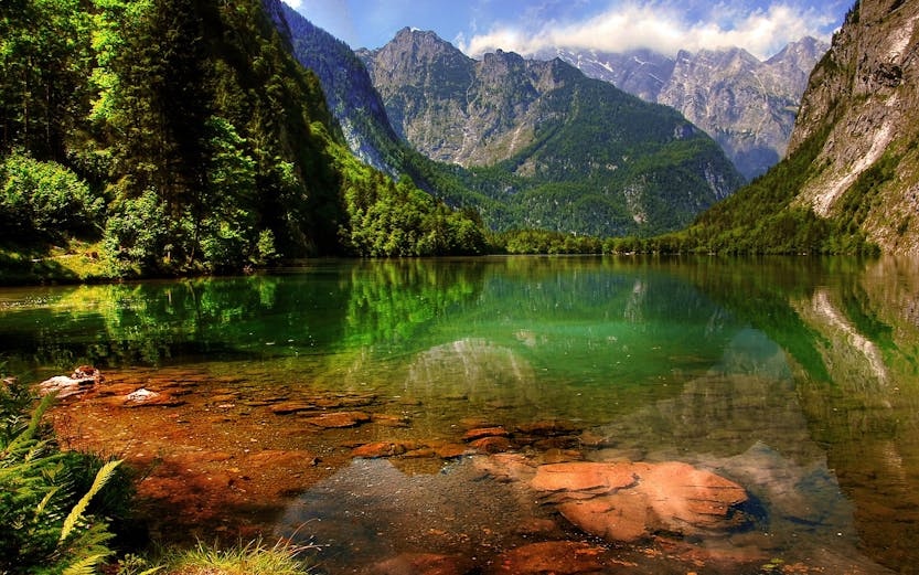 Berchtesgaden lake with mountain reflections and lush greenery.