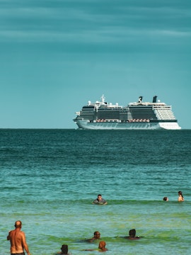 Cruise ship on Miami waters with people swimming nearby.