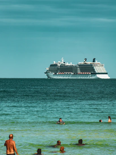 Cruise ship on Miami waters with people swimming nearby.