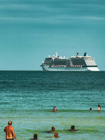 Cruise ship on Miami waters with people swimming nearby.