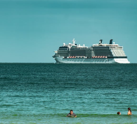 Cruise ship on Miami waters with people swimming nearby.