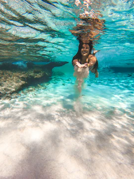Person swimming underwater in a clear cenote near Tulum, Mexico.