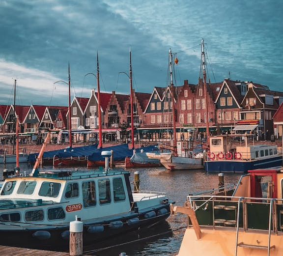 Boats docked at Volendam harbor with traditional Dutch houses in the background.