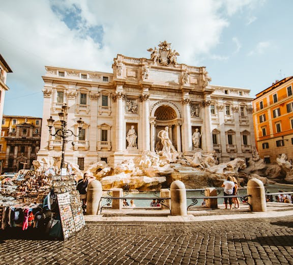 Trevi Fountain in Rome with tourists and street vendor nearby.