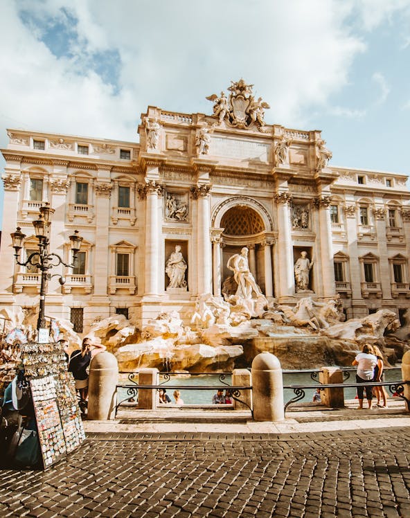 Trevi Fountain in Rome with tourists and street vendor nearby.