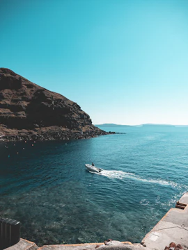 Speedboat on clear blue waters near rocky coast in Santorini, Greece.