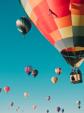 Hot air balloons floating in clear blue sky over Santorini.