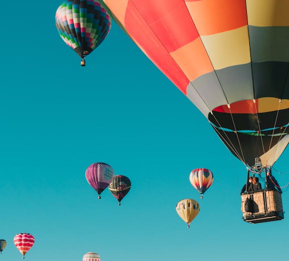 Hot air balloons floating in clear blue sky over Santorini.
