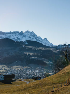 Scenic view of Appenzell countryside with snow-capped mountains and a rural house.