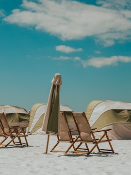 Beach chairs and umbrellas on Clearwater Beach, Florida, with tents in the background.