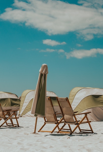 Beach chairs and umbrellas on Clearwater Beach, Florida, with tents in the background.