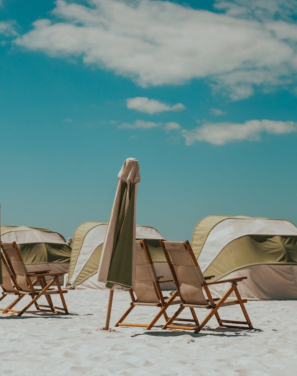 Beach chairs and umbrellas on Clearwater Beach, Florida, with tents in the background.