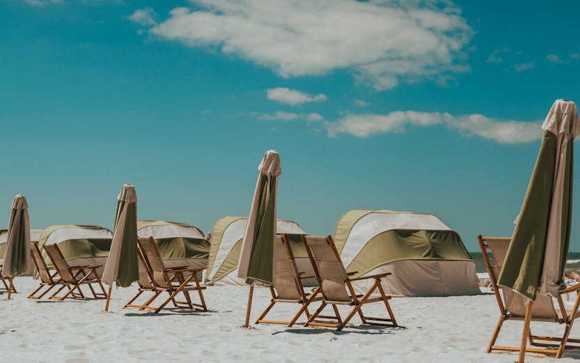 Beach chairs and umbrellas on Clearwater Beach, Florida, with tents in the background.
