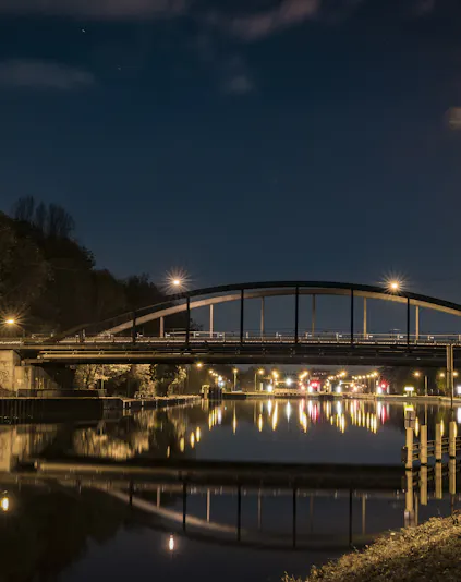 Bridge over a canal at night in Oberhausen, Germany, with streetlights reflecting on the water.