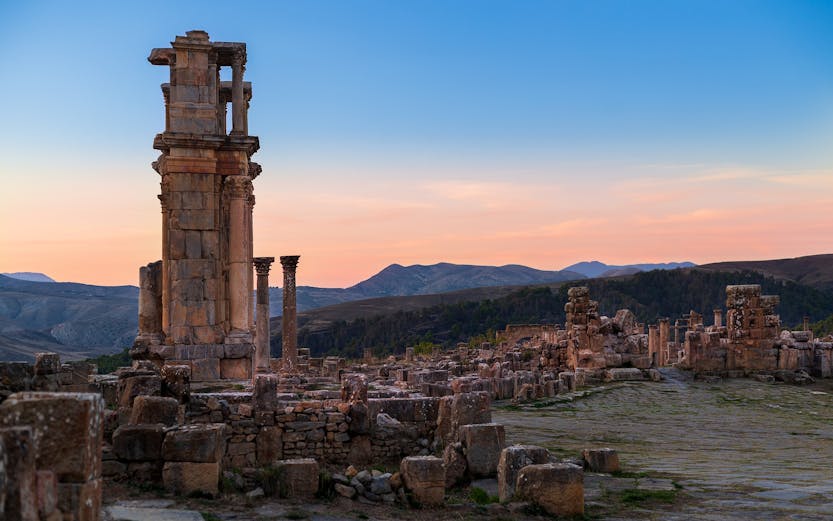 Ancient ruins with columns at sunset, resembling Baths of Caracalla.