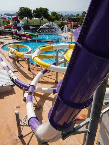 Illa Fantasia Water Park wave pool with families enjoying the water and slides in Barcelona, Spain.
