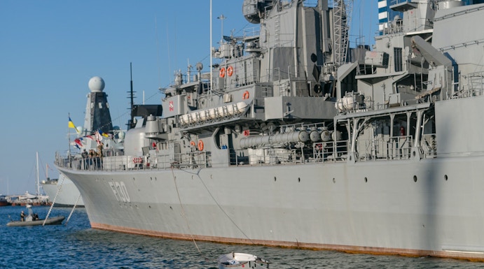 Battleship docked with small boats in the water, HMS Belfast tour.