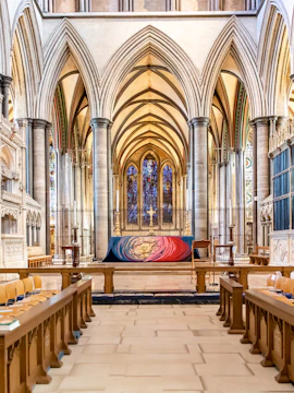 Salisbury Cathedral interior with vaulted arches and stained glass windows.