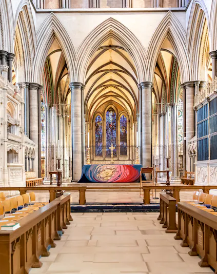 Salisbury Cathedral interior with vaulted arches and stained glass windows.