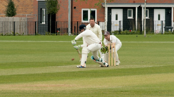 Cricketer batting at Kia Oval Cricket Ground with wicketkeeper and fielder.