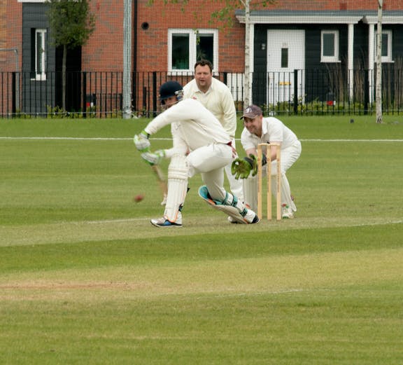 Cricketer batting at Kia Oval Cricket Ground with wicketkeeper and fielder.