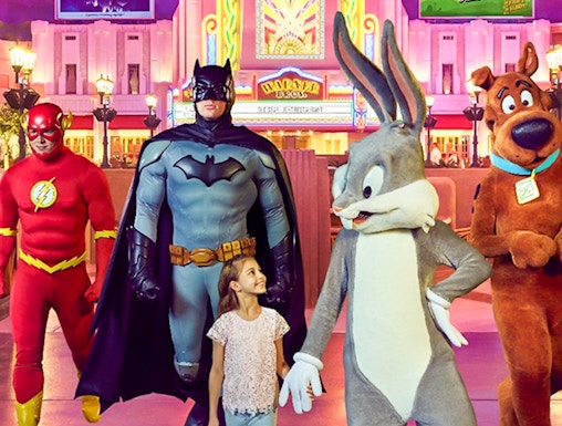 Child walking with Warner Bros characters at Abu Dhabi theme park.