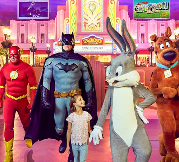 Child walking with Warner Bros characters at Abu Dhabi theme park.